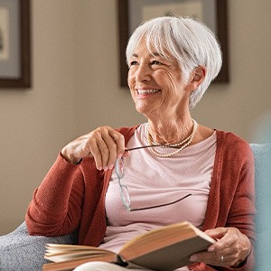 Woman smiling while reading book on couch at home