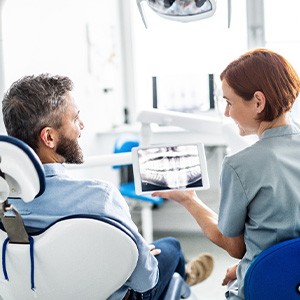 Smiling dental assistant and patient looking at X-ray