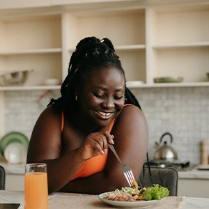 Woman smiling while eating lunch in kitchen