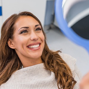 Woman smiling at reflection in handheld mirror