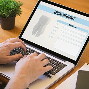 Patient filling out dental insurance form on laptop