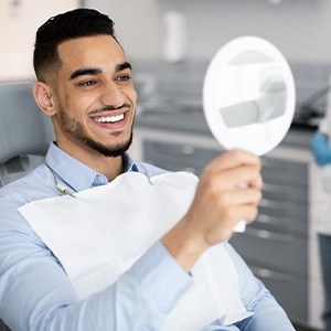 Man smiling at reflection in handheld mirror