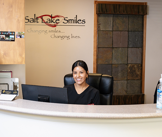 Smiling receptionist sitting at front desk at Salt Lake Smiles