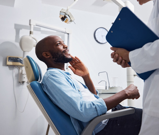 Patient smiling at dentist holding clipboard