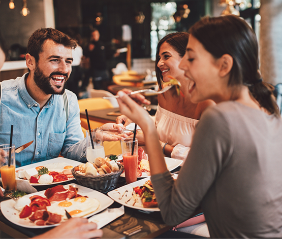Four adults sitting at a restaurant table and laughing together