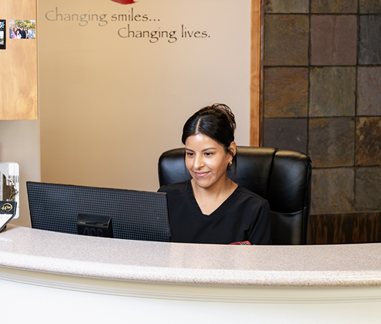 West Jordan dental team member at desk and looking at computer for dental insurance information