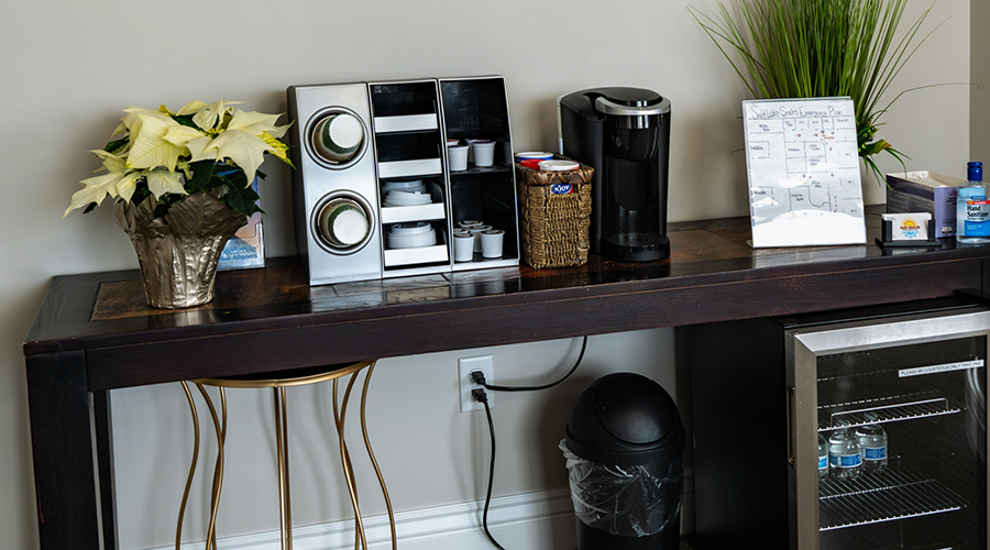 Coffee machine and mini fridge with water bottles in waiting area