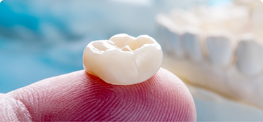 Close up of a dental crown resting on a finger