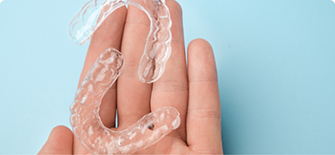 Hand holding two clear aligners