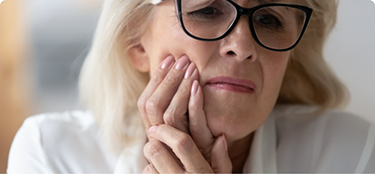 Woman wincing in pain and holding her cheek