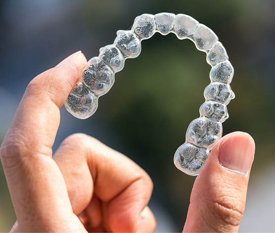 Hand holding a clear aligner