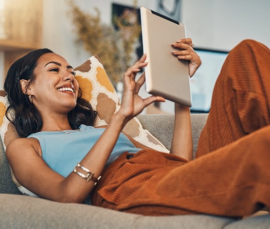 Smiling woman with tablet relaxing on couch