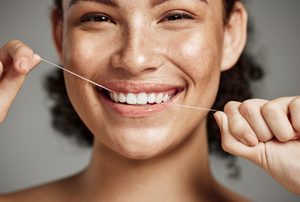 Woman smiling with holding floss in her teeth
